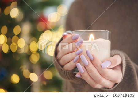 The hands of a young girl with a beautiful light purple manicure hold a candle The hands of a young girl with a beautiful light purple manicure hold a candle 106719105