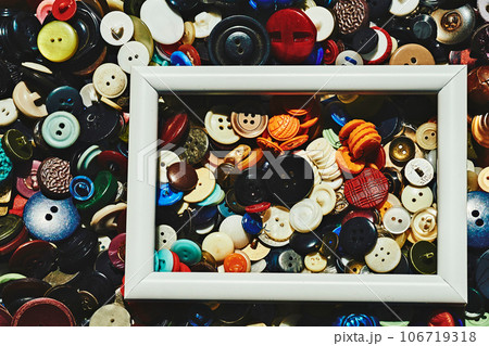 A bunch of different colored tailor's buttons and a white frame 106719318