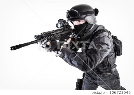 Spec ops police officer SWAT in black uniform aiming service rifle, studio shot 106723049