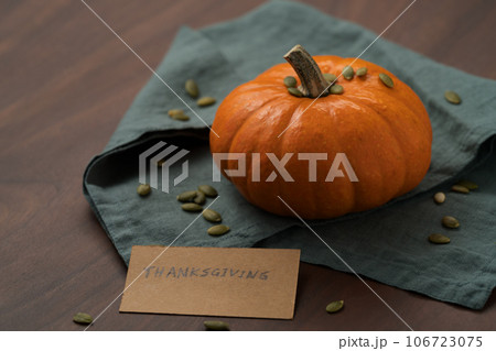 Orange pumpkin with seeds on wood table with thanksgiving paper card 106723075
