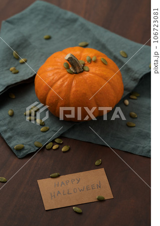 Orange pumpkin with seeds on wood table with halloween paper card 106723081