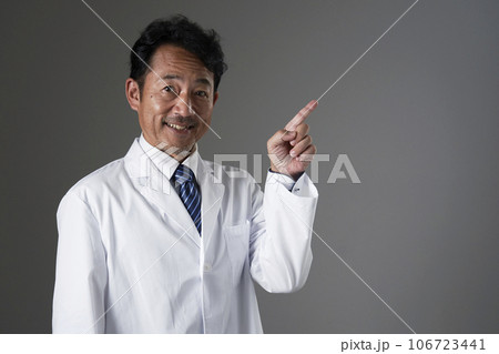右側を指差す中年の医師　黒背景 106723441