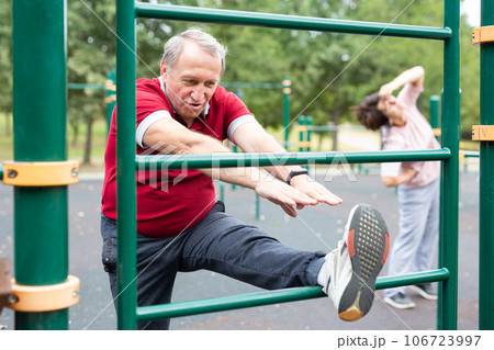 Elderly man doing leg stretching on the outdoor sports ground 106723997