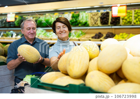 Senior married couple buy ripe melon in supermarket Senior married couple buy ripe melon in supermarket 106723998