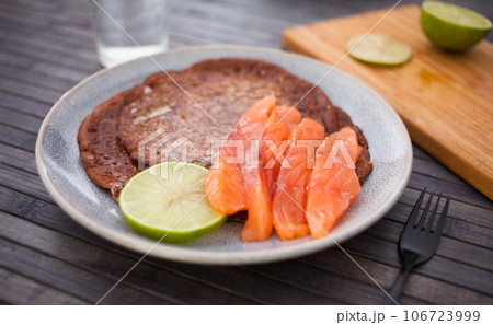 Salted salmon fillet with buckwheat pancakes and lime Salted salmon fillet with buckwheat pancakes and lime 106723999