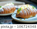 Sweet croissant sandwich dessert filled with whipped cream mixed with custard on blue plate  106724348