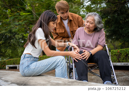 Asian careful caregiver or nurse taking care of the patient is hurting knee in wheelchair. Concept of happy retirement with care from caregiver and Savings and senior health insurance, a Happy family 106725212