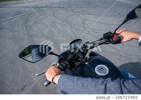 Caucasian man rides an electric motorcycle. Close-up of male hands on the steering wheel. Caucasian man rides an electric motorcycle. Close-up of male hands on the steering wheel. 106725468