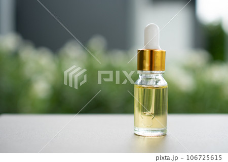 A glass bottle with dropper on the table. Concept of aroma oil, cosmetic, and beauty skin. A glass bottle with dropper on the table. Concept of aroma oil, cosmetic, and beauty skin. 106725615