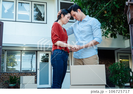 Man comforting his wife and woman hugging her husband and cry in front of the house and full of cardboard boxes during the transport in move out day, moving home concept 106725717