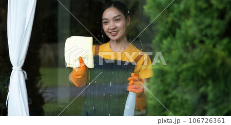 Housework and housekeeping concept. happy woman in gloves cleaning window with rag and cleanser spray at home Housework and housekeeping concept. happy woman in gloves cleaning window with rag and cleanser spray at home 106726361