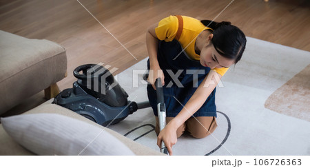 Young Asian woman using vacuum cleaner at home. floor in an apartment with a vacuum cleaner. Young Asian woman using vacuum cleaner at home. floor in an apartment with a vacuum cleaner. 106726363