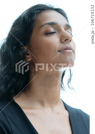 A portrait of a woman with closed eyes and a smile on a white background 106728132