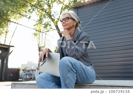 a gray-haired mature pretty business woman dressed in a stylish gray jacket and jeans sat down on a a gray-haired mature pretty business woman dressed in a stylish gray jacket and jeans sat down on a 106729138