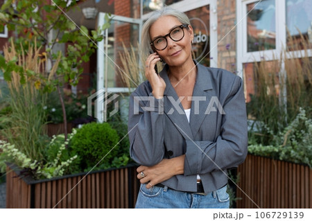 a slender European gray-haired senior business woman with a stylish hairstyle and glasses is dressed 106729139