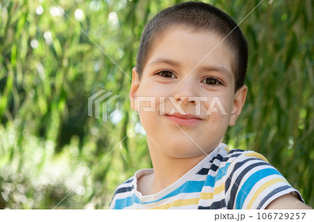 Portrait of a handsome six-year-old boy in a striped t-shirt in nature, a place for text to copy space 106729257