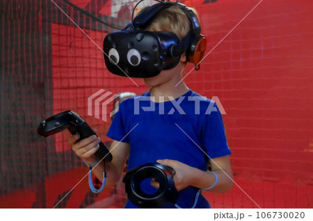 boy wearinga virtual reality headset plays video games in an arcade hall boy wearinga virtual reality headset plays video games in an arcade hall 106730020