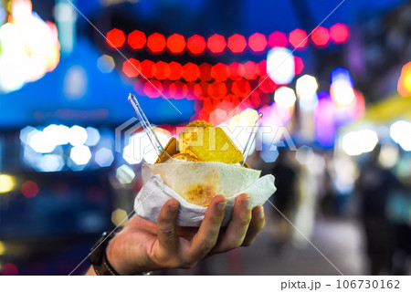 Hand holding coconut and mango ice cream in coconut shell in Jalan Alor street food market in Kuala Lumpur 106730162