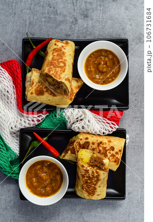 Mexican burritos with chorizo, potato, cheese and beef served with sauce borracha Mexican burritos with chorizo, potato, cheese and beef served with sauce borracha 106731684