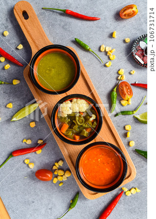 Three mexican sauces on wooden board with vegetables on gray background 106731714