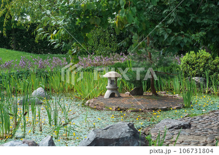 stone lantern on a small island in the middle of a pond in a Japanese garden 106731804