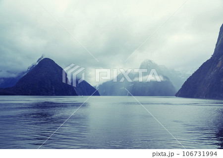 Photograph of mountains in clouds and mist in Milford Sound on the South Island of New Zealand Photograph of mountains in clouds and mist in Milford Sound on the South Island of New Zealand 106731994