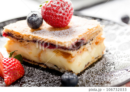 A piece of Napoleon cake with poppy seeds and cherries A piece of Napoleon cake with poppy seeds and cherries 106732033