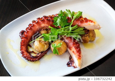 Boiled octopus tentacles according to a Mediterranean recipe with potatoes and parsley. Boiled octopus tentacles according to a Mediterranean recipe with potatoes and parsley. 106732242
