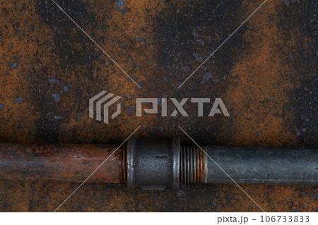 Rusty valve pipes on rusty metal wall 106733833