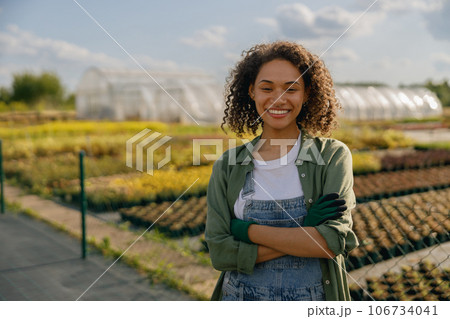 Smiling female agronomist standing on the field on greenhouses background. High quality photo Smiling female agronomist standing on the field on greenhouses background. High quality photo 106734041