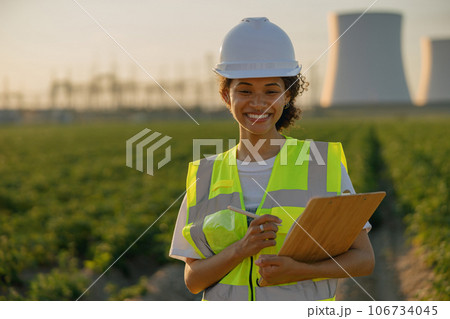 Female engineer constructor stands with clipboard on field on industrial enterprise background 106734045
