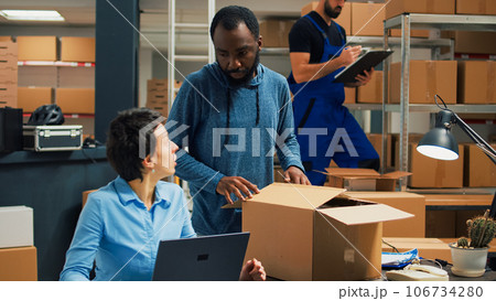 Small business owners doing quality control before shipping products order, packing merchandise in cardboard boxes. Workers preparing delivery and shipment in warehouse storage room. 106734280