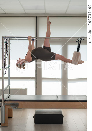 A pregnant woman is doing Pilates on a reformer. Aerial gymnastics.  106734400