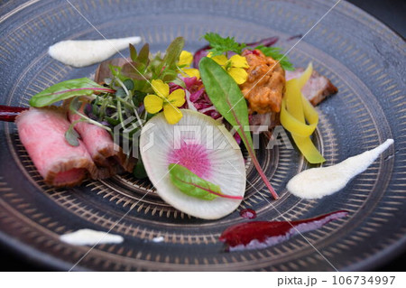 食用花や香草などで華やかに盛り付けられた黒毛和牛ローストビーフ 106734997