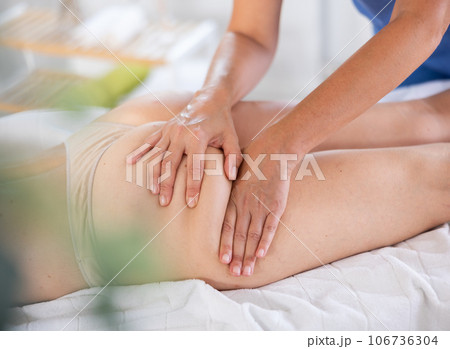 Hands of masseuse giving glutes and hamstring massage to woman Hands of masseuse giving glutes and hamstring massage to woman 106736304