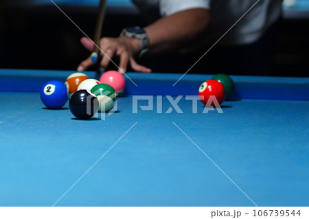 The hand holding the billiard cue, ready to make a precise strike on the billiard ball on the billiard table in a game of billiards. 106739544
