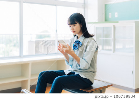 スマホを持つパンツスタイルの女子高生 106739934