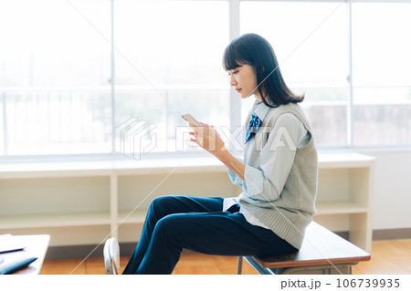 スマホを持つパンツスタイルの女子高生 106739935
