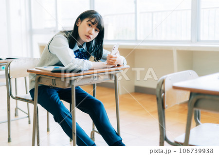 女子高生　机の上　パンモロ スマホを持つパンツスタイルの女子高生の写真素材 [106739938] - PIXTA