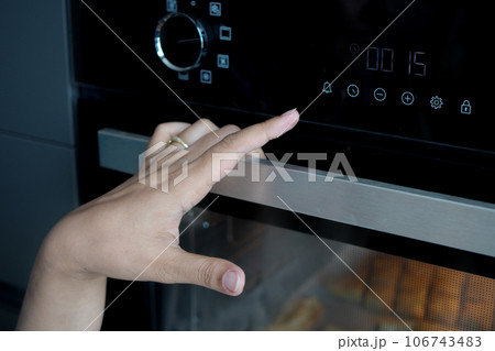 woman hand setting temperature control on oven. woman hand setting temperature control on oven. 106743483