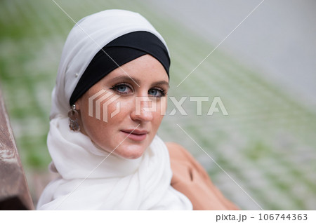 Portrait of a young blue-eyed woman in a hijab outdoors. Portrait of a young blue-eyed woman in a hijab outdoors. 106744363