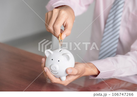 Businessman hand putting bitcoin into white piggy bank Businessman hand putting bitcoin into white piggy bank 106747266