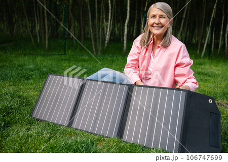 Woman holding solar panel in garden. 106747699