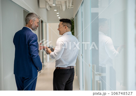 Men walking along corridor in office and talking about their work. 106748527