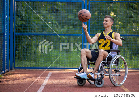 Wheelchair basketball player holding, disability, outdoor basketball court. Wheelchair basketball player holding, disability, outdoor basketball court. 106748806