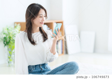 リビングでスマホを操作する若い女性 リビングでスマホを操作する若い女性 106749873