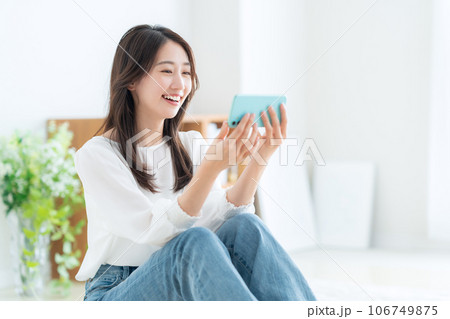 リビングでスマホを操作する若い女性 リビングでスマホを操作する若い女性 106749875