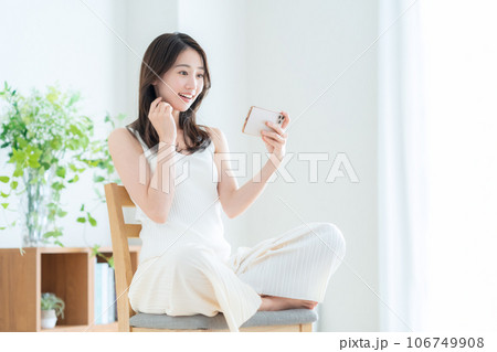 リビングでスマホを操作する若い女性 106749908