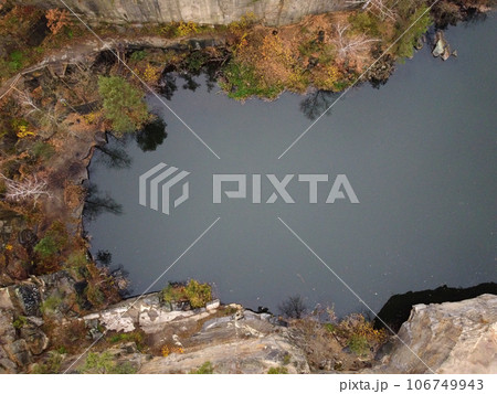 Picturesque aerial view of landscape with emerald lake and rocks in the middle of a coniferous autumn forest in Korostyshiv granite quarry, Zhytomyr district, northern Ukraine. Zhytomyr canyon 106749943