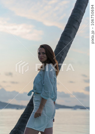 portrait of brunette girl standing at dawn against a palm tree portrait of brunette girl standing at dawn against a palm tree 106750694